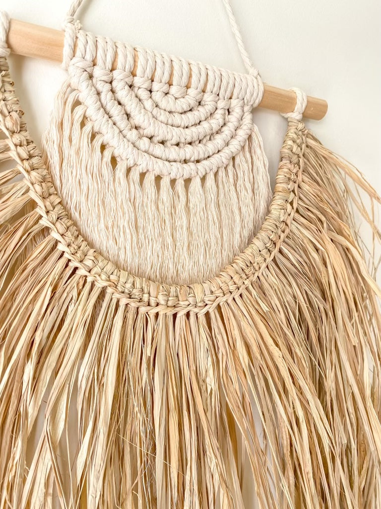 Close up view of a macrame and raffia wall hanging hanged on a wall 
