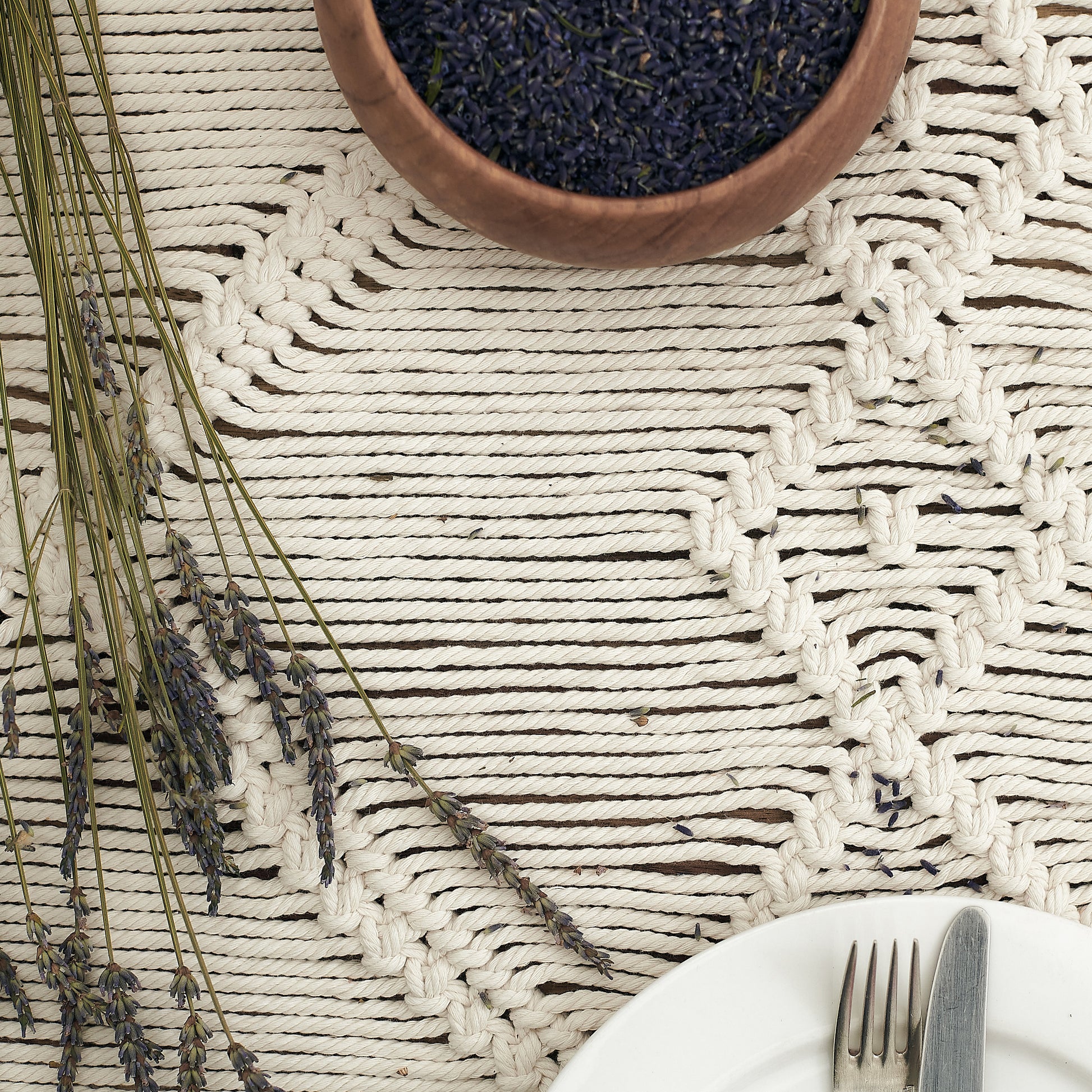 Natural white macrame table runner on a wooden table styled with rustic dried Lavender and pottery