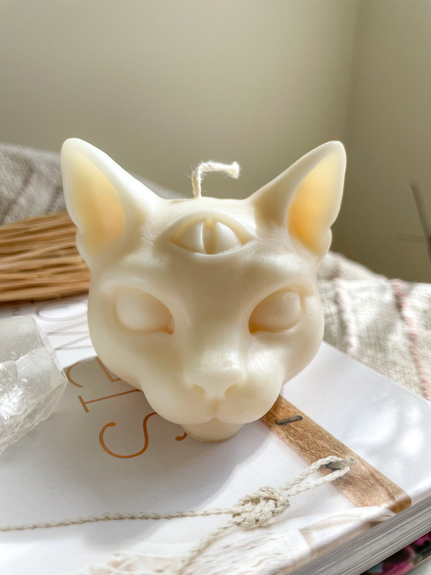 Third eye cat candle styled on a coffee table book with crystals and rattan ornaments