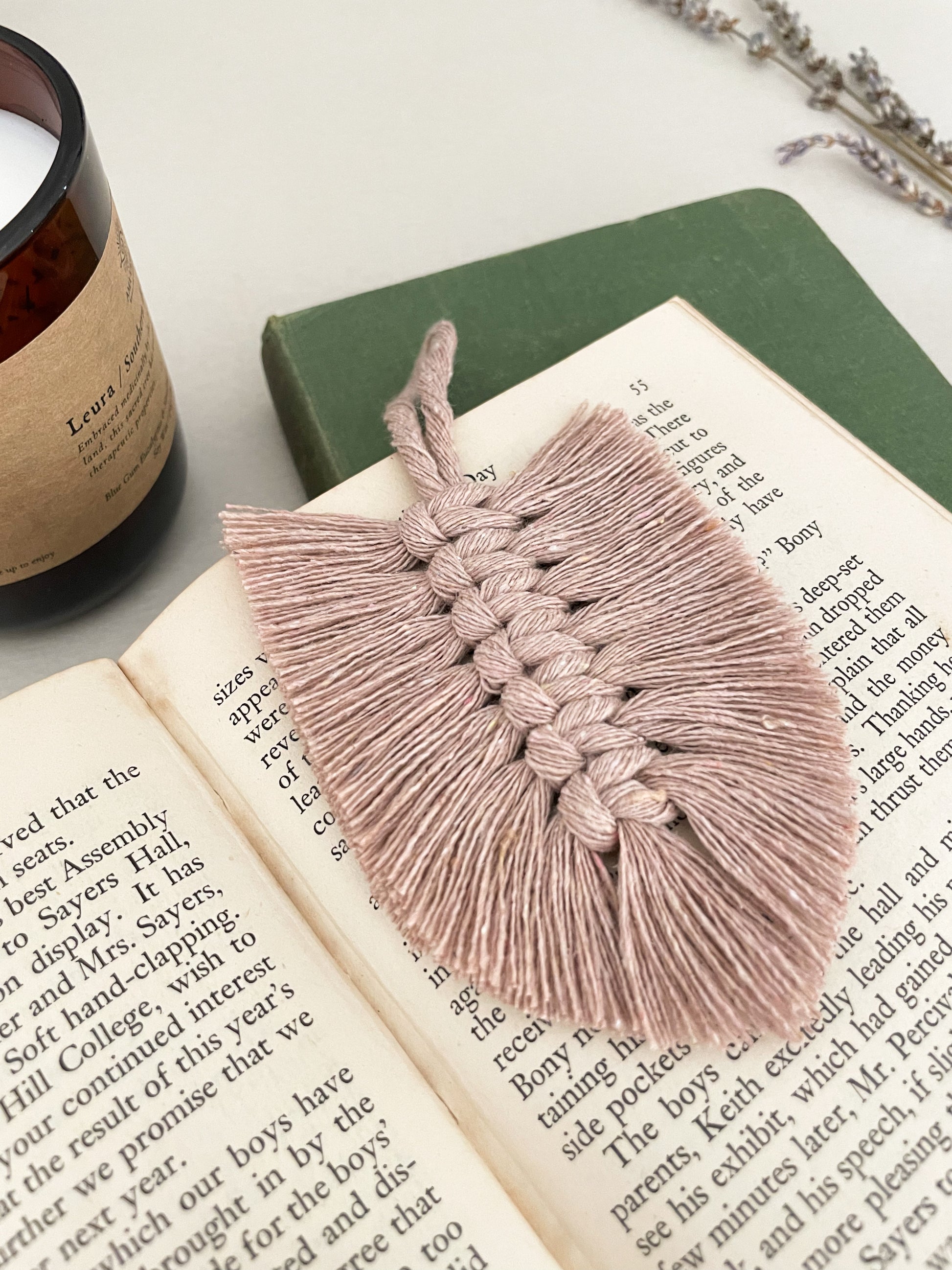 Handmade macrame feather bookmark placed on a book. 