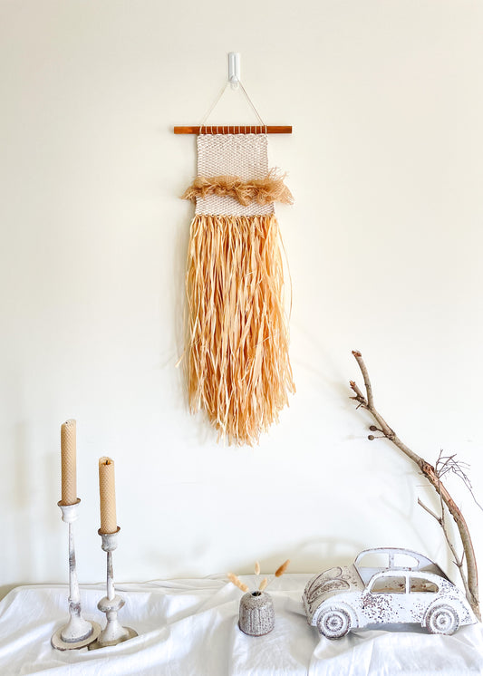 Mermaid raffia wall hanging hanged on a wall above a side board styled with candles, handmade pottery, rustic car and dried branches