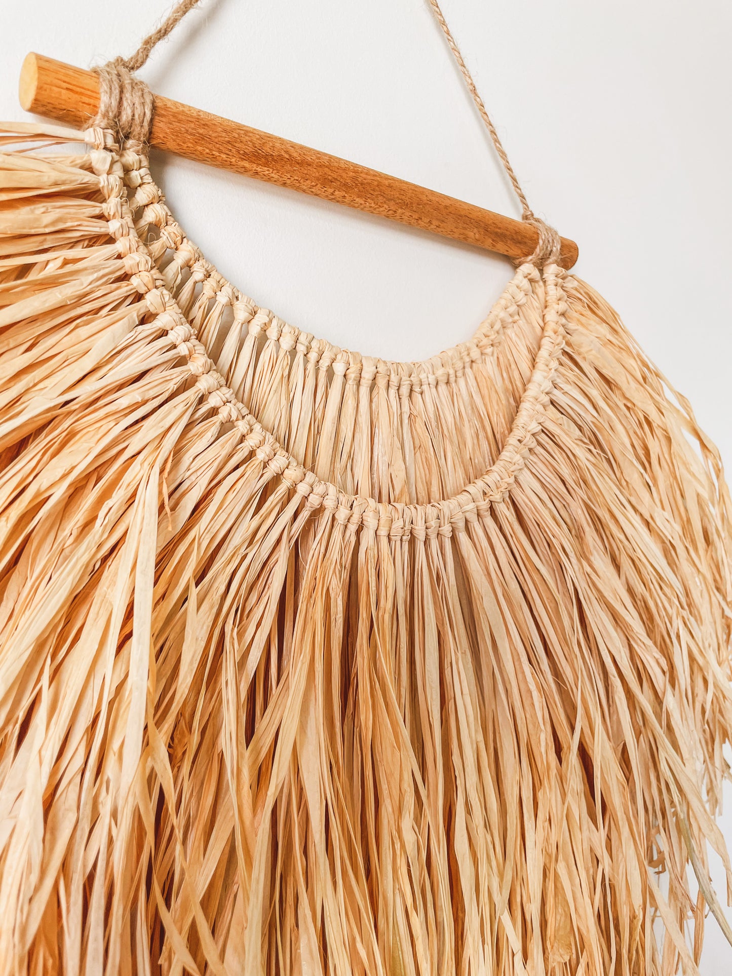 Closeup view of a raffia wall hanging from a side. 