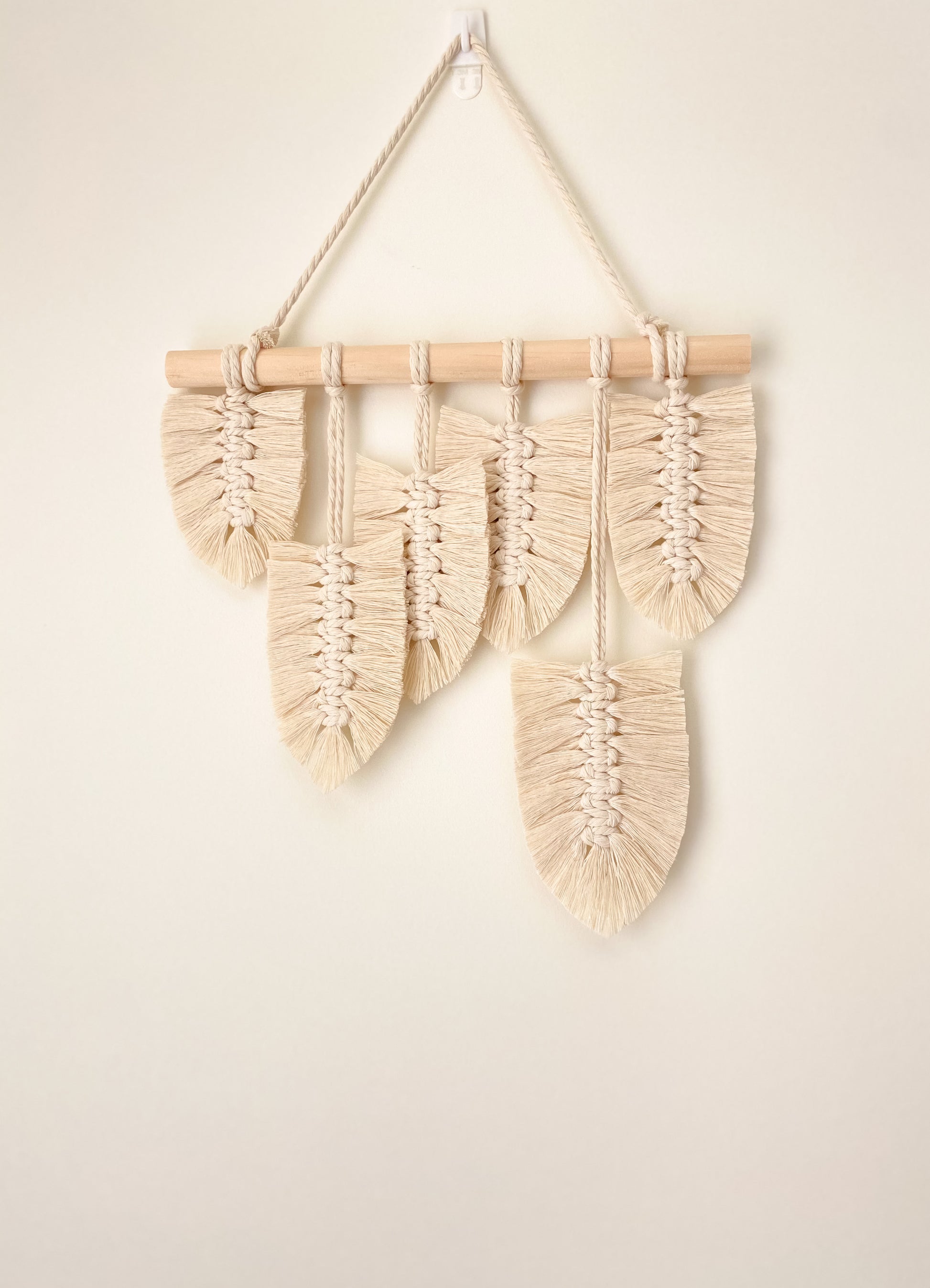 Natural white macrame feather wall hanging hanged on a wall