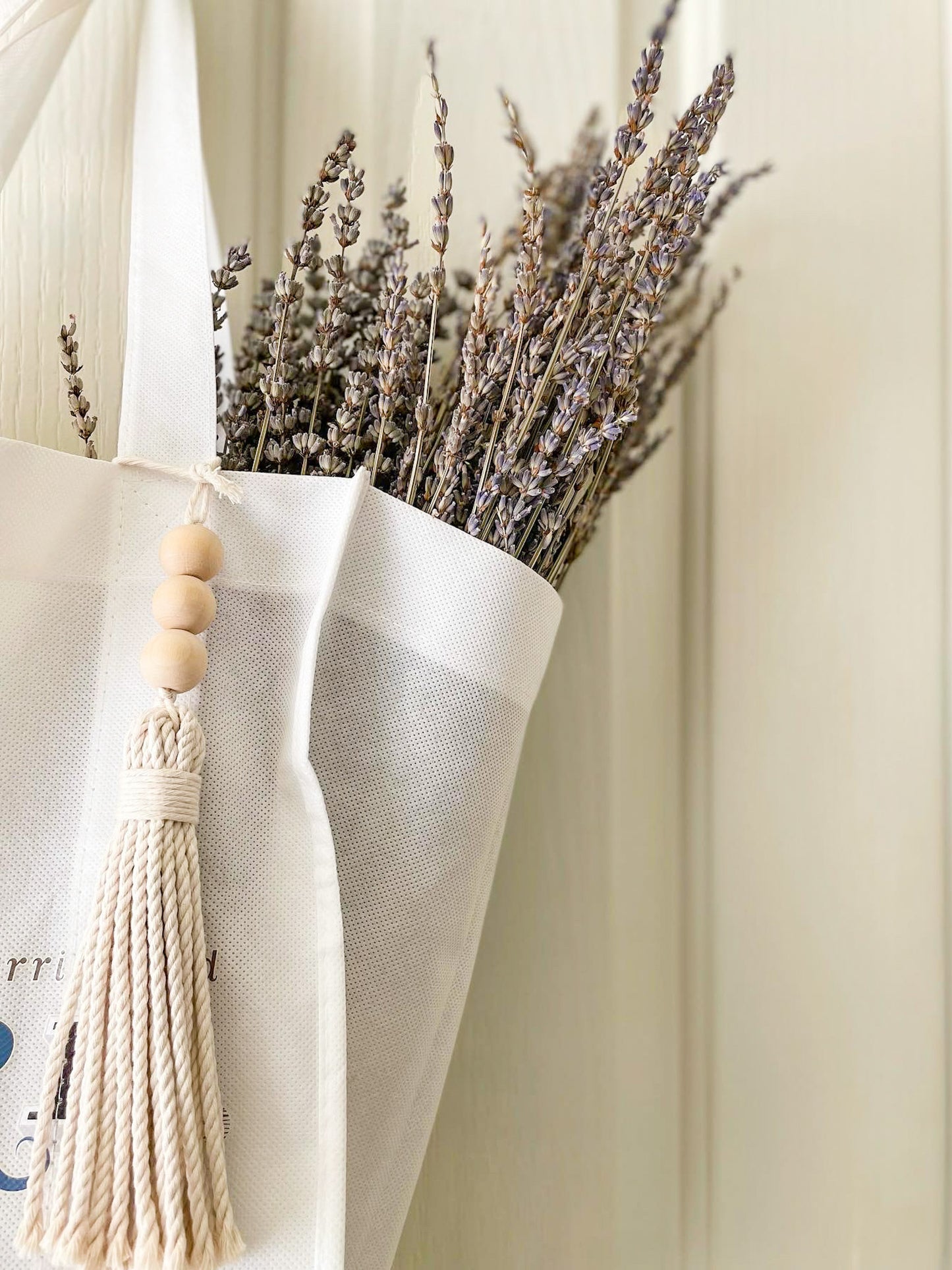 Beaded macrame tassel hanged on a tote bag. Dried lavendar flowers inside the bag. 