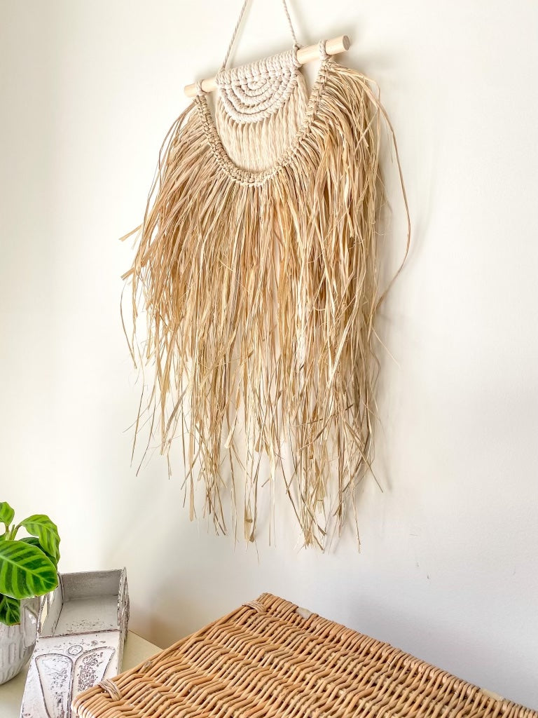 Macrame and raffia wall hanging hanged on a wall above a buffet table side view