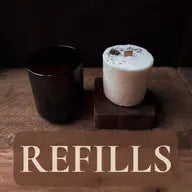 Our Leura soywax scented candle refills displayed in s rustic setting next to a amber reusable candle jar
