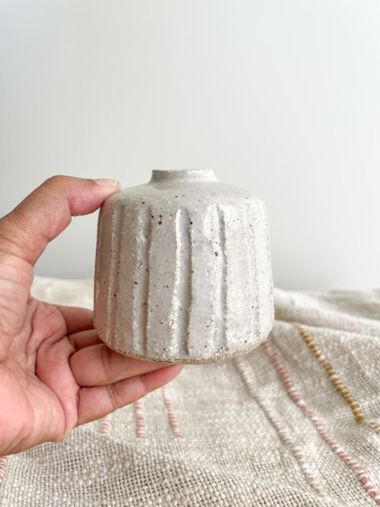 Small white ceramic vase held by hand